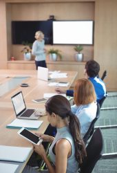 High angle view of businesswoman using digital tablet while sitting at conference table during meeting